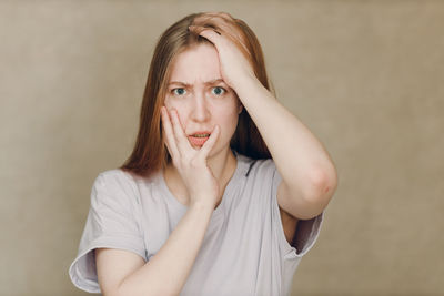 Portrait of young woman standing against wall