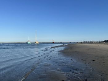 Sailboats on beach against clear blue sky