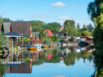 Houses by lake and buildings against sky