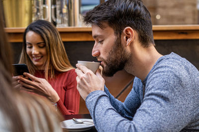 Young man and woman using mobile phone in cafe