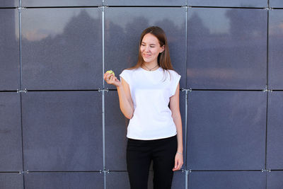 Portrait of young woman standing against wall