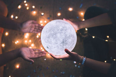 Directly above shot of woman giving illuminated crystal ball to friend