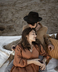 Boyfriend kissing girlfriend relaxing on beach during picnic