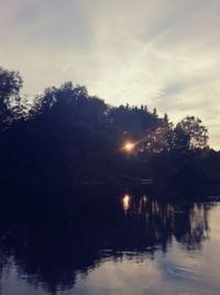 Silhouette trees by lake against sky during sunset