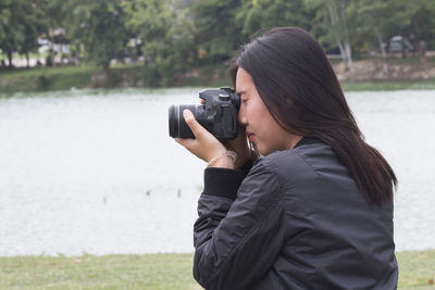 Woman photographing against lake