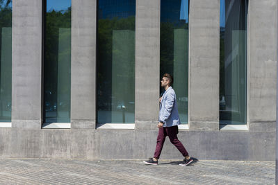 Full length of young man standing against wall