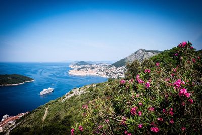 Scenic view of sea and mountains against clear blue sky