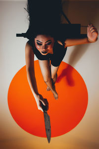 High angle view of young woman holding knife on floor