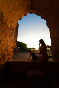 Side view of man sitting on archway