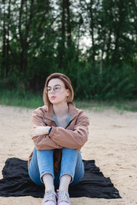 Candid portrait of a young caucasian woman with short hair sitting on sand at the beach