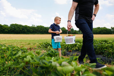 Rear view of father with son standing on field