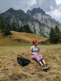 Woman sitting on land against mountains