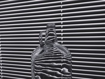 Close-up of glass jar against blinds