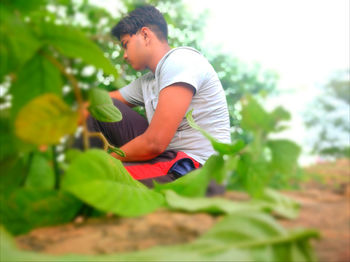 Side view of young man looking at plants
