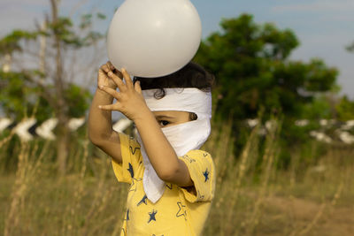 An asian boy enjoys unlocking covid-19 and holding white balloon in two hands 