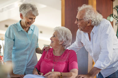 Senior woman signing a contract, friends reassuring her