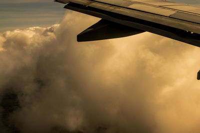 Airplane wing against cloudy sky