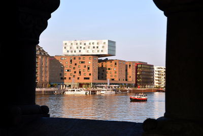 Buildings by sea against clear sky