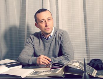 Portrait of businessman reading books while sitting at table