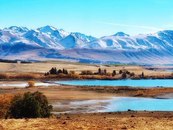 Scenic view of lake and mountains against blue sky