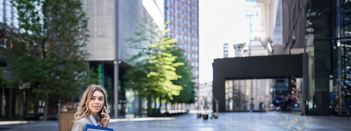 Portrait of young woman standing in city