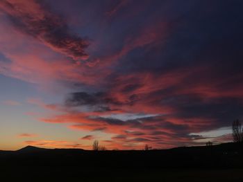 Silhouette landscape against dramatic sky during sunset