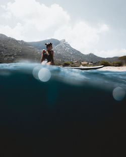 Man in lake against sky