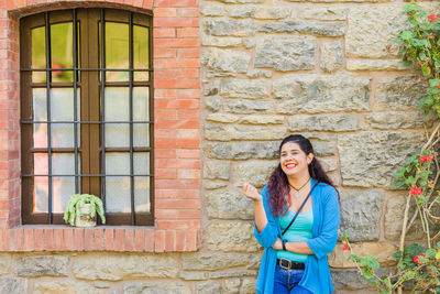 Portrait of young woman standing against wall