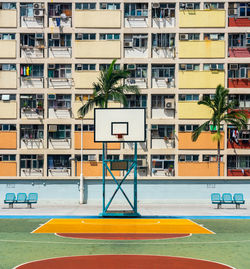 Basketball hoop on sports court against building in city