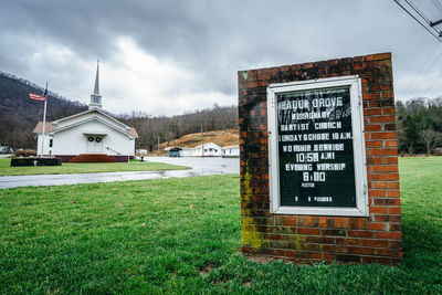 Information sign on field against sky