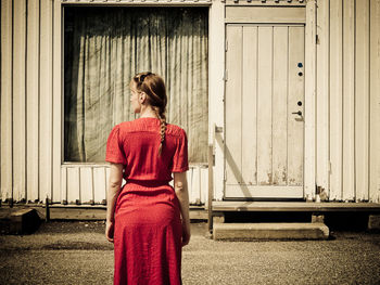 Rear view of young woman standing against wall