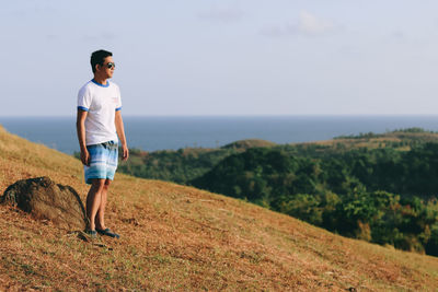 Full length of young man standing on land against sky