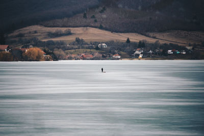 Distant view of person standing on frozen lake