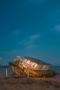 Abandoned boats on beach against blue sky