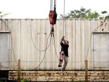 Full length of man hanging on rope against wall