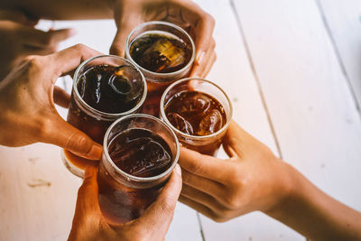 Cropped image of friends holding drink glasses at table