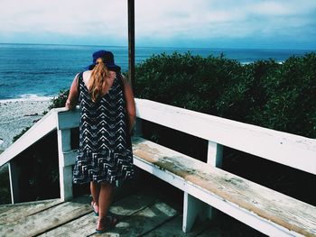 Rear view of woman standing by sea