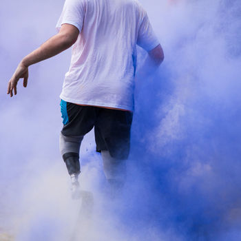 Low section of disabled person walking in blue powder paint