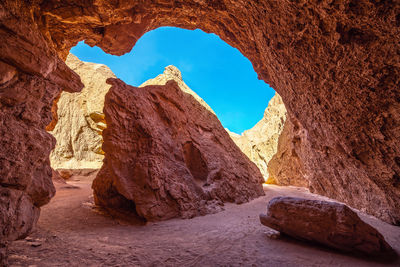 Tourists on rock formation against blue sky