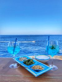 View of drink on table at sea against clear blue sky
