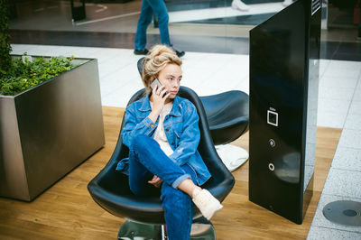 Woman talking on mobile phone while sitting on chair