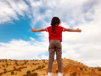 Rear view of boy standing against sky