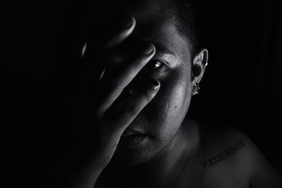 Portrait of shirtless man with hand on face against black background