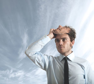 Portrait of young man looking away against sky