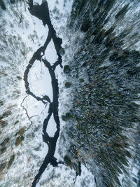 Aerial view of stream flowing amidst snow covered land