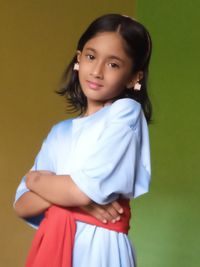 Portrait of young woman standing against wall