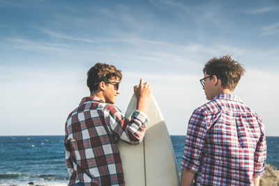 Friends standing by sea against sky