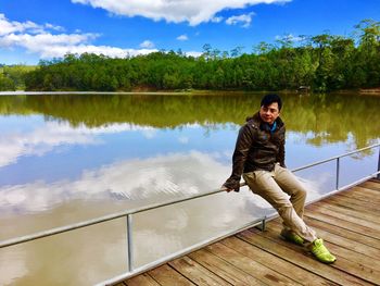 Man standing on riverbank against sky