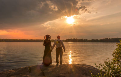 Friends enjoying in lake against sky during sunset