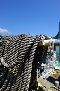 Close-up of rope tied on metal against blue sky